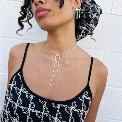 GORGEOUS SILVER BOW EARRINGS Displayed in a lifestyle setting with a model wearing a bow chocker.