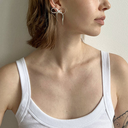 GORGEOUS SILVER BOW EARRINGS featuring a clean chic bow design and modern nature silver and black color ,perfect for dailylife/party/office/casual occasion.Displayed in a lifestyle setting with a model wearing a white tank.