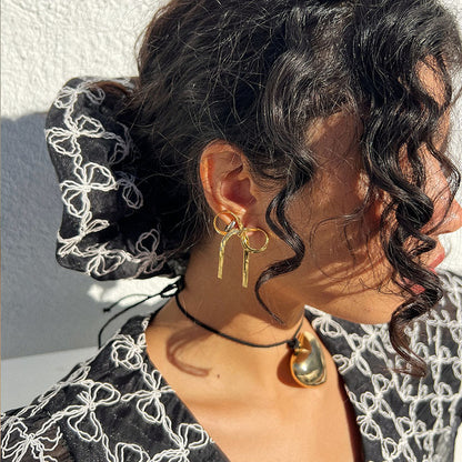 GORGEOUS GOLD BOW EARRINGS GORGEOUS GOLD BOW EARRINGS featuring a clean chic bow design and modern nature gold and black color ,perfect for dailylife/party/office/casual occasion. Displayed in a lifestyle setting with a black curly hair model wearing a  lot of bow accessories.