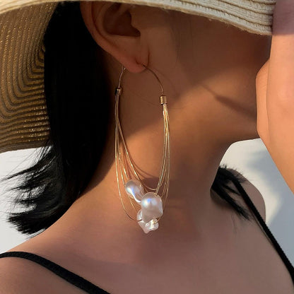 GORGEOUS GIANT BAROQUE PEARL GOLD HOOP EARRINGS featuring a clean chic design and modern white color ,perfect for dailylife/party/office/casual occasion. Displayed in a chill vacation vibe setting with a model wearing a elegant straw hat.