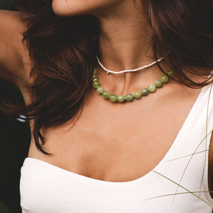 SOPHIA GREEN BOWL BEACH BALI NECKLACE featuring a clean chic design of Dyed green quartz & Glass beads in middle size and vintage green color with gold necklace clasp ,perfect for dailylife/party/office/casual occasion. Displayed in a romantic vacation vibe setting with a model wearing a white summer outfit.