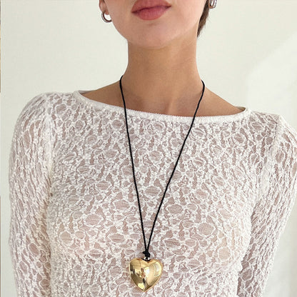 Puffy 3D Heart Necklace featuring a clean chic design and modern nature gold and black braided rope  ,perfect for dailylife/party/office/casual occasion. Displayed in a lifestyle setting with a model wearing a summer  lace outfit.