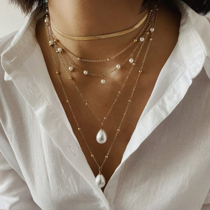 MULTI LAYER WATER DROP PEARL PENDANT WEDDING NECKLACE featuring a clean chic design and modern nature gold and pearl color ,perfect for dailylife/party/office/casual occasion. Displayed in a chic lifestyle setting with a model wearing a white shirts .