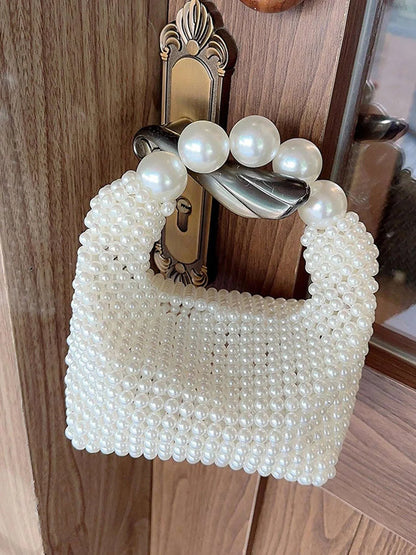 STATEMENTS OF HANDMADE PEARL BEADED HANDBAG WHITE featuring a clean chic pearl of big and small design  ,perfect for dailylife/party/office/casual occasion. Styled against a wooden door background.