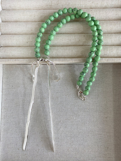 Chloe VINTAGE GREEN BEADED RIBBON NECKLACE featuring a clean chic bow design of Dyed green quartz & Glass beads in small size and vintage green color with gold necklace clasp ,perfect for dailylife/party/office/casual occasion. Styled against a nature fabric background.