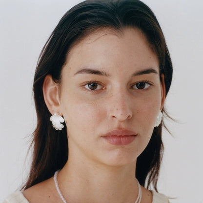 SOFT PEARL FLOWER PETAL EARRINGS featuring a clean chic  flower petal with silver design and modern white pearl  ,perfect for dailylife/party/office/casual occasion. Displayed in a lifestyle setting with a elegant model wearing a white beaded necklace.