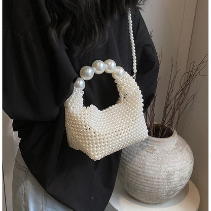 STATEMENTS OF HANDMADE PEARL BEADED HANDBAG WHITE featuring a clean chic pearl of big and small design  ,perfect for dailylife/party/office/casual occasion. Displayed in a chill lifestyle setting with a model wearing a black outfit