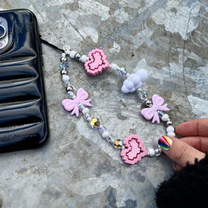 Lisa The Princess Wristlet Phone Strap Close-up of a stylish wristlet phone strap in durable material, featuring a secure loop for easy carrying and a sleek high quality white pearl and pink cloud/bows/ heart bead design for everyday convenience.