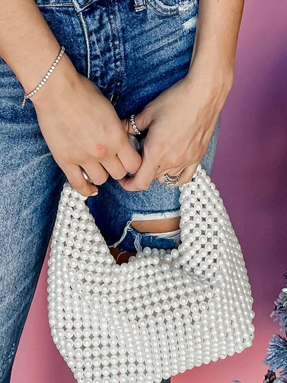 STATEMENTS OF HANDMADE PEARL BEADED HANDBAG WHITE featuring a clean chic pearl of big and small design  ,perfect for dailylife/party/office/casual occasion. Displayed in a lifestyle setting with a model wearing a blue jeans outfit.